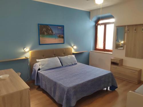 a blue bedroom with a bed and a window at B&B Relax Gonone in Cala Gonone