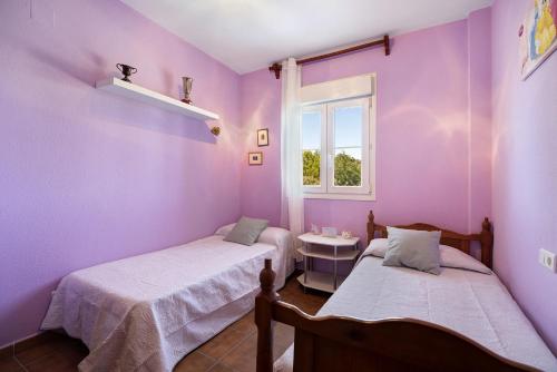 a purple room with two beds and a window at Casa Costa Ballena Dahlia in Costa Ballena