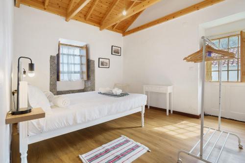 a bedroom with a white bed in a room with wooden ceilings at Adega Peróla in Cais do Galego
