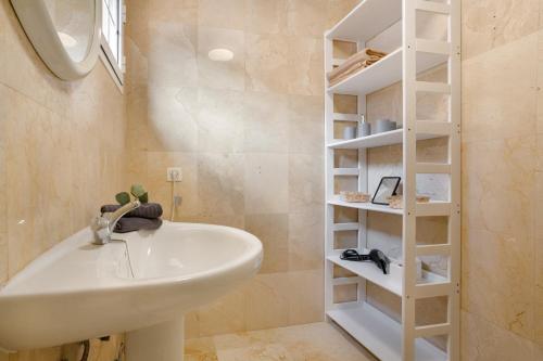 a bathroom with a white sink and a shelf at Casa Yeray in Caleta De Fuste