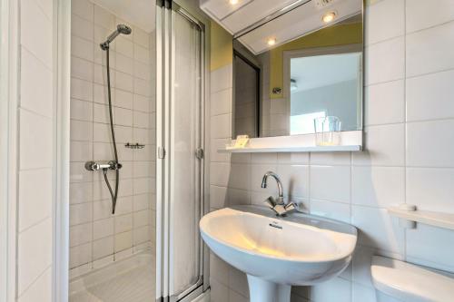 a white bathroom with a sink and a shower at La Demeure Océane in Portsall