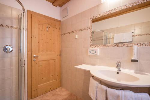 a bathroom with a sink and a mirror and a shower at App Lisüra Cir in Corvara in Badia