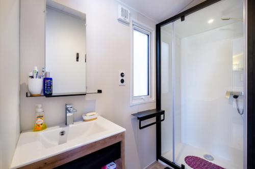 a white bathroom with a sink and a shower at Mobil-Home Baia in Saint-Raphaël