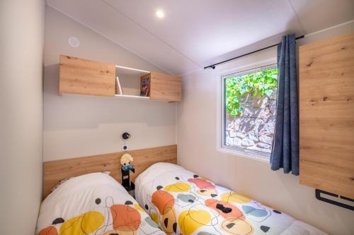 two beds in a small room with a window at Mobil-Home Baia in Saint-Raphaël