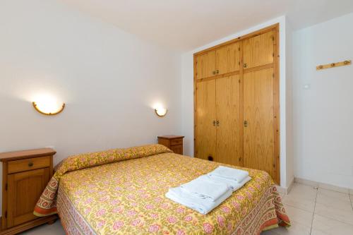 a bedroom with a bed with two towels on it at White Sands Maluz in Arenal d'en Castell