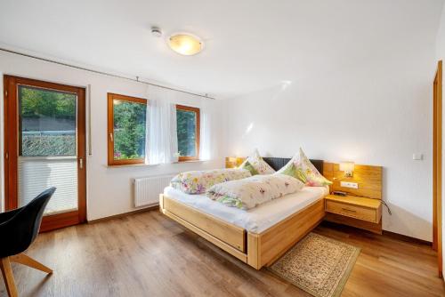 a bedroom with a bed and a desk and windows at Pension Schneider in Freiamt