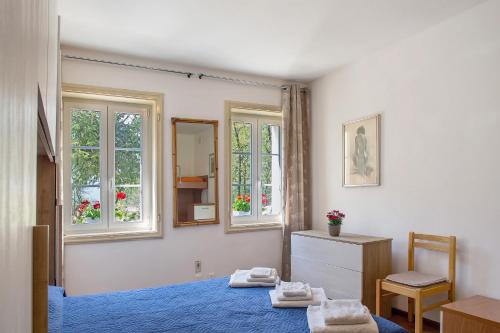 a bedroom with a blue bed and two windows at Villa Stanga in Sedico