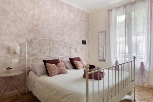 a bedroom with a white bed with pink pillows at La Rosa Dei Venti in Vernazza