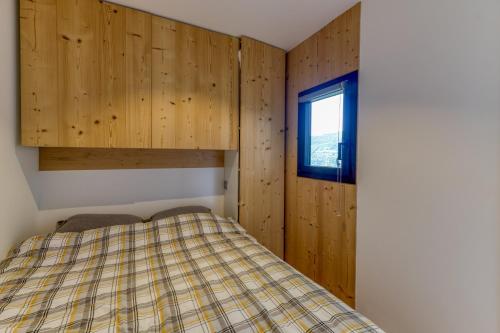 a bedroom with wooden walls and a bed with a window at Appartement Alpe d'huez in LʼHuez