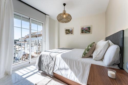 ein Schlafzimmer mit einem Bett und einem großen Fenster in der Unterkunft Oasis Mijas Centro in Mijas