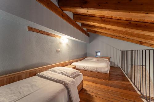 two beds in a room with wooden floors and wooden ceilings at Civico 5 in Marmora