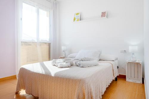 a white bedroom with a bed with towels on it at Dorada Apartment Mar in Calafell