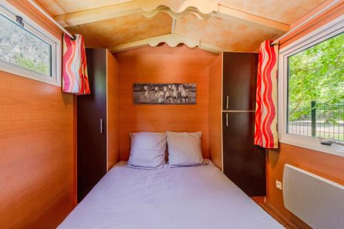a small bedroom with a bed in a tiny house at Roulotte insolite terrasse nature in Touët-sur-Var