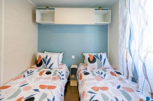 two twin beds in a small room with blue walls at Camping Les Oyats in Seignosse