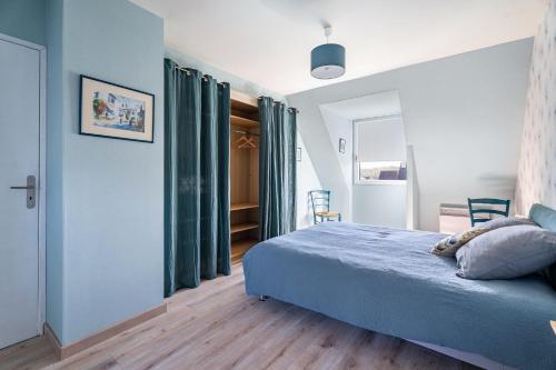 a bedroom with a blue bed and green curtains at Gîte Ty Berniques in Pléneuf-Val-André