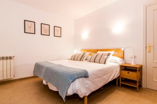 a bedroom with a large white bed and a night stand at Drac Blanc 1-3 in Cala Ratjada