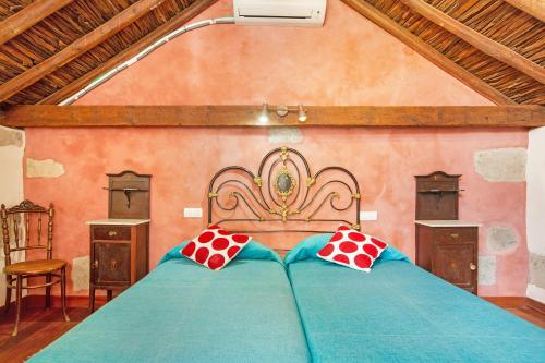 a bedroom with a blue bed with red and white pillows at Casa Emblemática La Pileta Bentejui in Agüimes