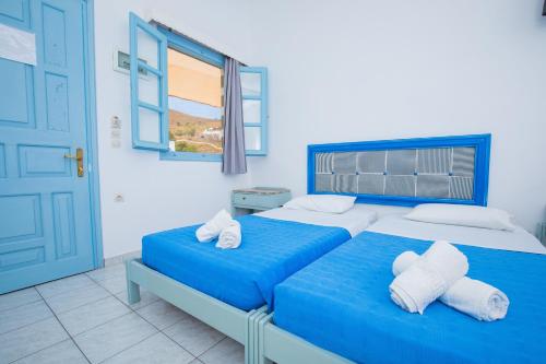 two beds in a bedroom with a blue door at Pico Bello Patmos 12 in Patmos