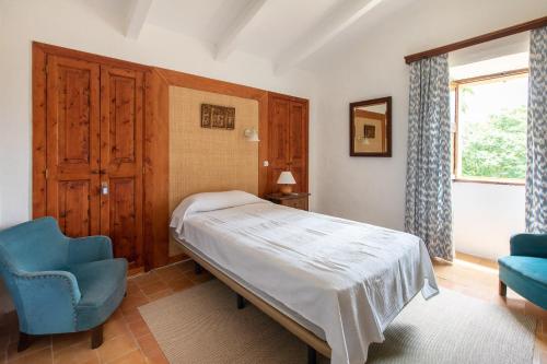a bedroom with a bed and a chair and a window at Ca'n Pont in El Port
