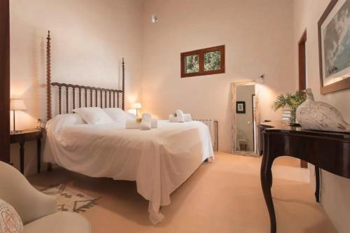 a bedroom with a large white bed and a table at Can Garí in Sóller