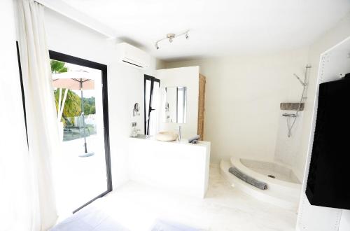 a white bathroom with a tub and a toilet at Villa La Vida in Cala Llonga