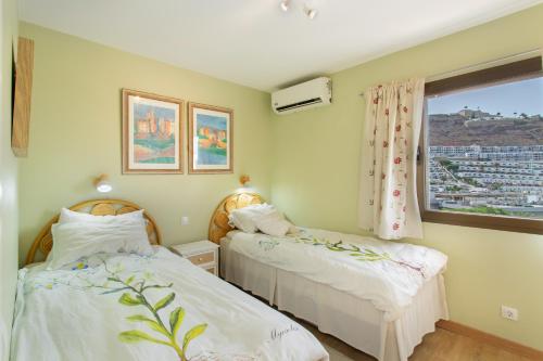 two beds in a room with a window at Eucalipto-Sun guaranteed-pool wifi in Puerto Rico de Gran Canaria