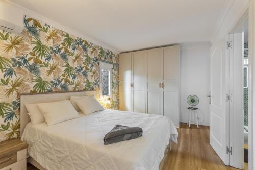 a bedroom with a white bed with a tropical wallpaper at Monterojo San Agustin Las Burras in San Agustin