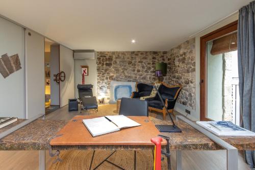 a living room with a table and a stone wall at Kel Domènech Luxury Apartment in Besalú