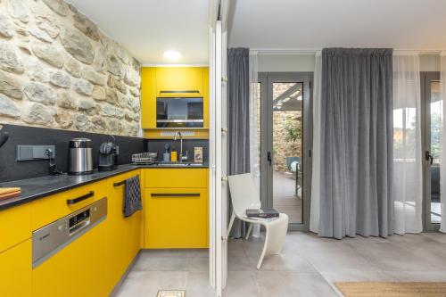 a kitchen with yellow cabinets and a table and chairs at Kel Domènech Luxury Apartment in Besalú