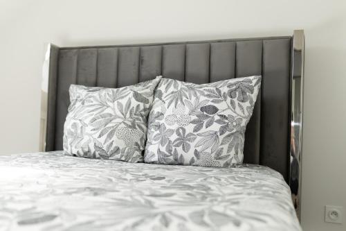 a bed with two pillows and a gray headboard at Appart 2 morangis in Morangis