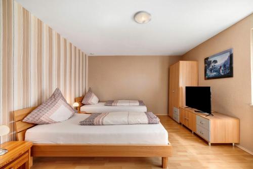 a hotel room with two beds and a flat screen tv at Ferienwohnung Eleonore in Meßstetten