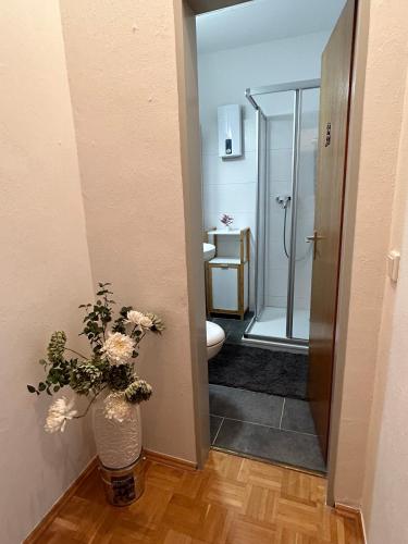 a bathroom with a toilet and a vase with flowers at Minas Ferienwohnung in Dormagen