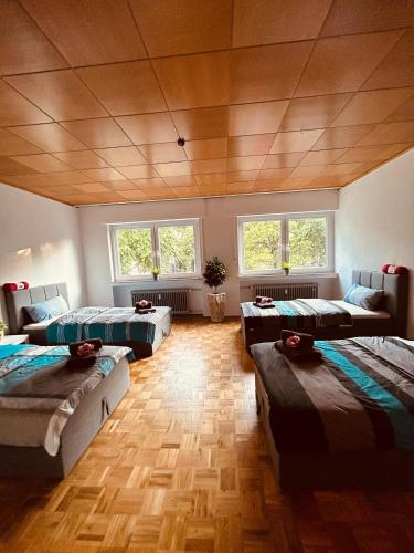 a large room with three beds and windows at Minas Ferienwohnung in Dormagen