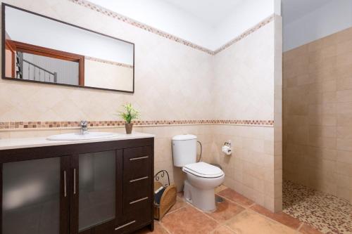 a bathroom with a toilet and a sink and a mirror at Villa Selena in Pájara