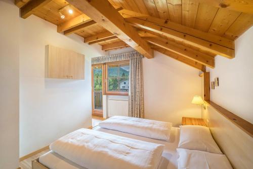 two beds in a room with wooden ceilings at Oberhölzlhof in Valdaora di Sopra