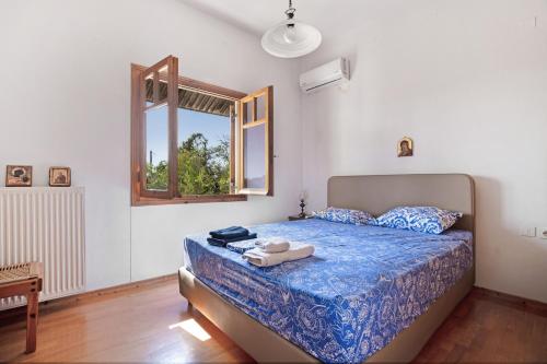a bedroom with a bed with a blue comforter and a window at Villa Sugar Town in Zacharo