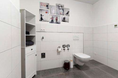 a white bathroom with a toilet and pictures on the wall at White House Apartments in Kappel-Grafenhausen