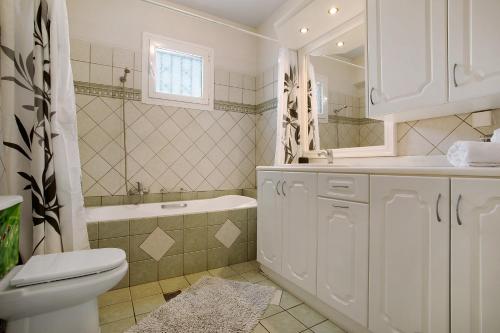 a bathroom with a toilet and a tub and a sink at Christine's House in Zakynthos