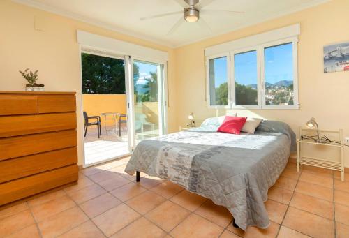 a bedroom with a bed and a dresser and windows at Verano in Calpe