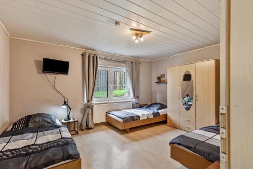 a bedroom with two beds and a tv and a window at App und Fewos Wolf in Usingen