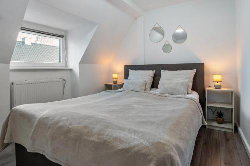 a white bedroom with a large bed with two lamps at Ferienwohnung zur Grenze in Gronau