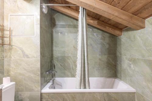 a bath tub in a bathroom with a wooden ceiling at Les Petits Loups in Morillon