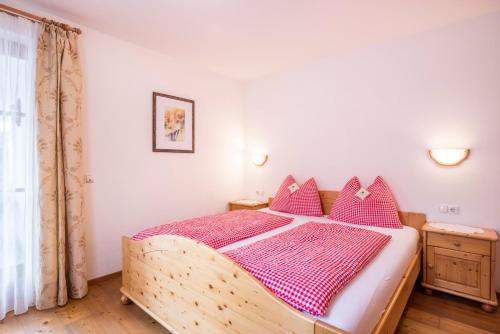 a bedroom with a wooden bed with pink pillows at Ciasa Tlara App Alma in San Vigilio Di Marebbe