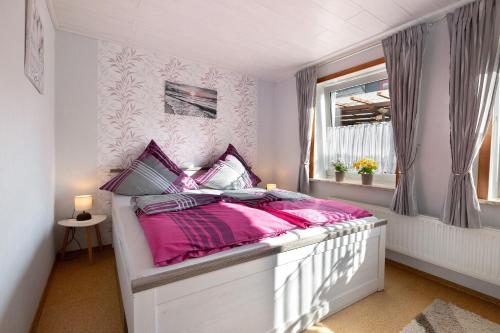 a bedroom with a bed with pink sheets and a window at Bi Tiessens to Hus in Arkebek