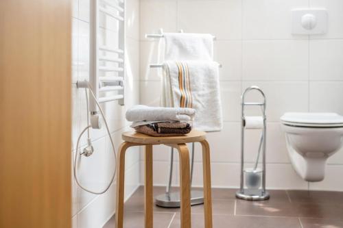 a bathroom with a toilet and a stool with towels at Ferienwohnung 2 Schulze in Neustrelitz