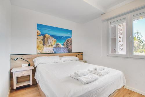 a white bedroom with a bed with towels on it at Kuko Beach Denia in Denia