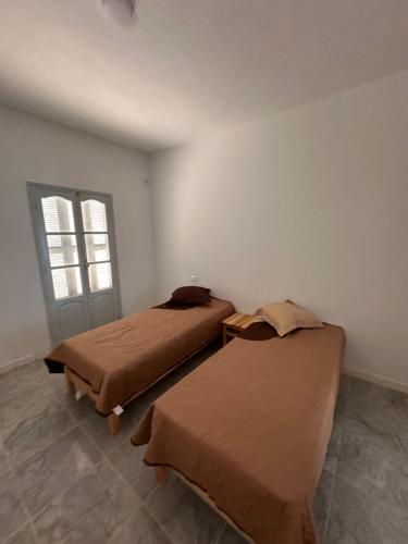 two beds in a room with a window at Appartement melita aéroport in Mellita