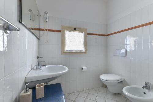 a white bathroom with a sink and a toilet at Appartamento con vista mare Chiessi in Chiessi