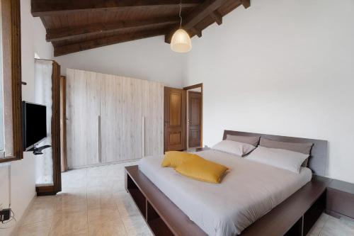 a bedroom with a large white bed with a yellow pillow at La mansarda di Mariuccia in Castelletto sopra Ticino