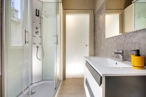 un bagno con doccia e lavandino bianco di Dongo Garden a Dongo